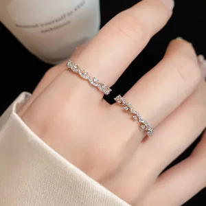 Detailed view of a minimalist wavy zircon ring worn on a finger.