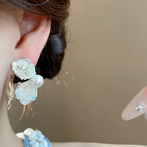 Detail view of butterfly wing pearl earrings with sparkling crushed stone texture