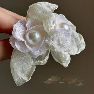 Primer plano de elegantes pendientes de flores de gasa blanca con detalle de perla