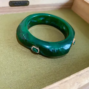 Close-up detail of a marbled green resin bangle with embedded emerald-style stones.
