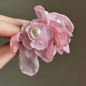 Exquisito detalle macro de pendientes de flores de gasa rosa con detalles de perlas