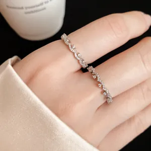 Macro detail of an elegant silver zircon lace ring with a wavy design on a finger