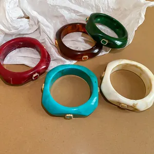 Close-up of colorful resin bracelets with inlaid gemstones and niche design details.