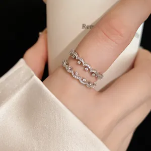 Detailed shot of two delicate silver-toned wavy rings set with sparkling zircons