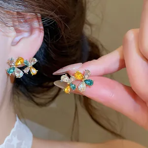 Primo piano di orecchini a lobo a fiore con strass colorati e gemme a goccia eleganti