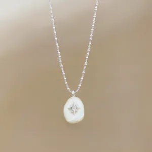 Close-up of cotton pearl pendant with silver North Star on ball chain necklace.