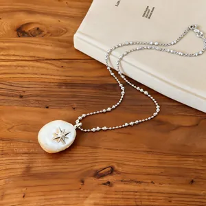 Detailed view of elegant star pendant necklace with a baroque pearl on a wooden background