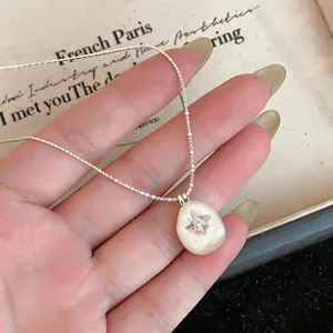 Close-up detail of a minimalist cotton pearl necklace with a dainty silver star pendant