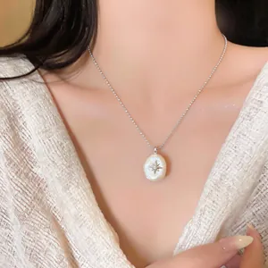 Close-up of starburst pendant necklace with white pearl on model's neckline