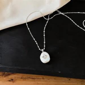 Close-up of minimalist star charm pearl necklace on elegant black and white background
