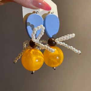 Vintage handmade earrings featuring blue wood drops, pearl bead bows and large yellow resin beads