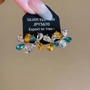 Dettaglio di orecchini floreali con strass colorati su uno sfondo neutro calmo