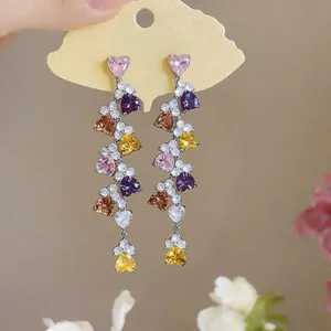 Close-up of colorful heart-shaped zircon tassel earrings shown on a display card