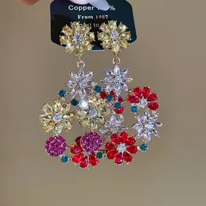 Dettaglio di eleganti orecchini floreali multicolori con strass scintillanti e rame.