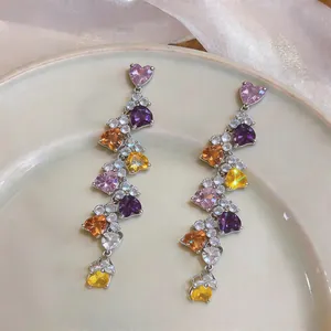 Detail view of colorful heart-shaped zircon stones on long dangle tassel earrings