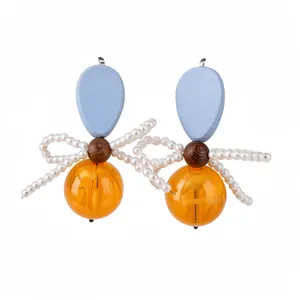 Elegant vintage wooden and resin bow earrings featuring pearl accents and orange beads