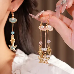 Elegant gold-tone drop earrings featuring ocean charms like shells, starfish, and pearls