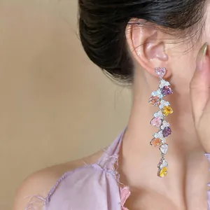 Detail shot of long tassel earrings with colorful heart-shaped zircon stones on model.