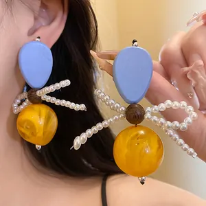 Close-up of vintage resin and wood bow earrings with pearl accents and amber sphere.