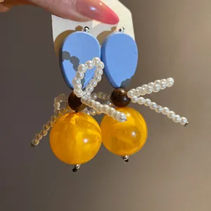 Detailed view of vintage-style earrings with blue wood, yellow resin beads and pearls