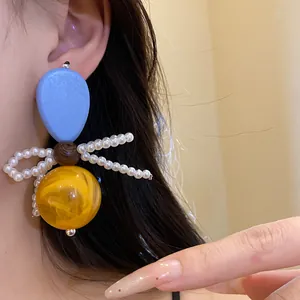 Close-up of vintage butterfly earrings with wood, pearls, and amber resin spheres.