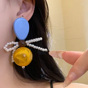 Detailed close-up of vintage resin pearl bow earrings featuring wood beads and yellow sphere.