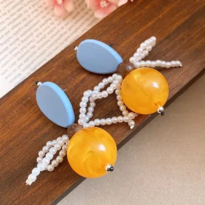 Detailed view of vintage resin and pearl earrings with blue wood and amber spheres.