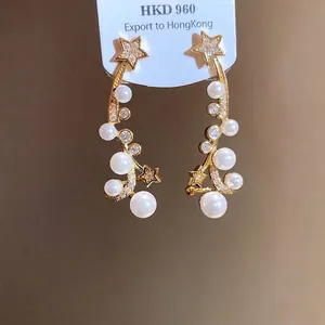 Elegant gold-tone star and pearl drop earrings featuring sparkling zircon accents