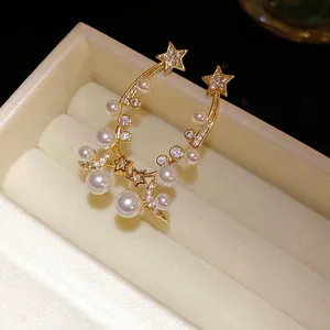 Elegant gold-tone celestial star earrings with zircons and pearls in a jewelry box display