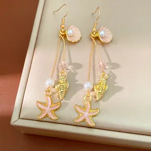 Close-up view of elegant gold starfish and shell dangle earrings with pearls for vacation