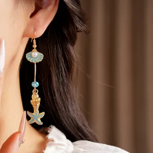 Close-up detail of beach-themed dangling earrings with blue starfish and pearl shell charms
