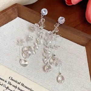 Detailed view of silver needle earrings with shimmering glass water drop tassels