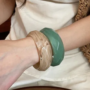 Eleganti bracciali in acrilico marmorizzato e sfaccettato al polso, design di nicchia