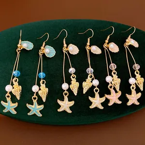 Detailed view of ocean-themed drop earrings with starfish, shells, and pearls on green velvet