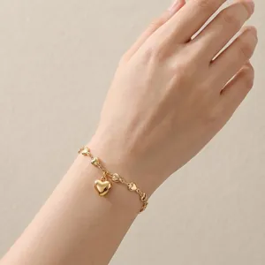 Detailansicht eines 18k Gold-Herzanhänger-Armbands am Handgelenk für einen eleganten Look