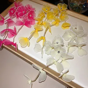 Detail view of handmade mesh flower tassel earrings with rhinestones in multiple colors.