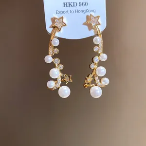 Detailed macro view of elegant gold-toned star earrings with white pearls and zircon