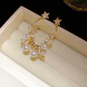 Close-up of elegant star and pearl stud earrings with zircon accents in a gift box