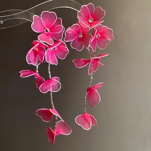 Close-up detail of handmade pink mesh flower earrings with rhinestones and silver needles