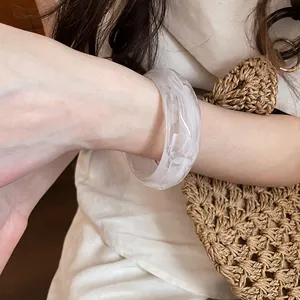 Dettaglio di un bracciale in acrilico marmorizzato bianco indossato da una modella