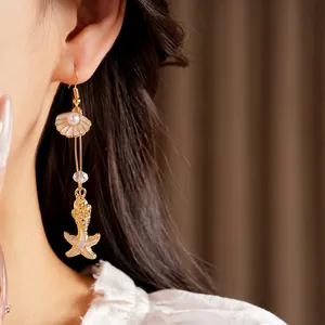 Detailed close-up showing beach-style shell and starfish pearl drop earrings on ear