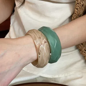 Primo piano di bracciali in acrilico marmorizzato e sfaccettato sul polso della modella