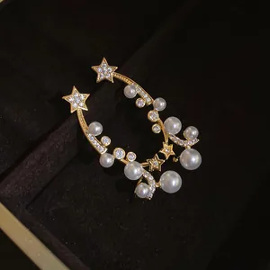 Close-up of elegant gold-tone earrings with zircons, stars, and pearls in a velvet box