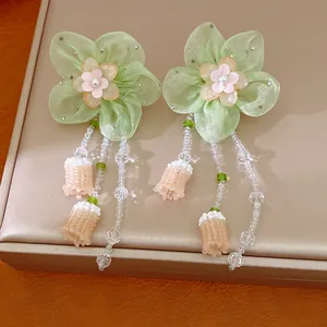 Detailed view of handmade green chiffon flower earrings featuring elegant beaded tassels.
