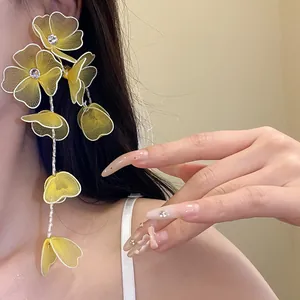 Close-up of yellow mesh flower tassel earrings with rhinestones on a model