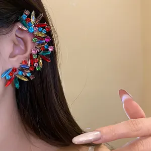 Primo piano dettagliato di un lussuoso ear cuff con strass colorati sull'orecchio del modello