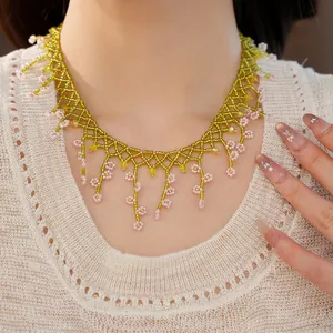 Detail view of a handcrafted Bohemian beaded necklace with delicate pink flower accents