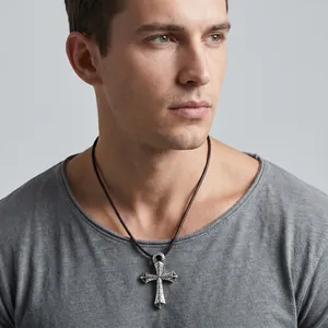 Detalle de colgante de cruz gótica en un modelo masculino con camiseta gris