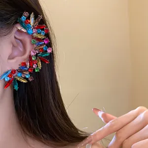 Dettaglio di un ear cuff di lusso con cristalli colorati e strass irregolari sull'orecchio