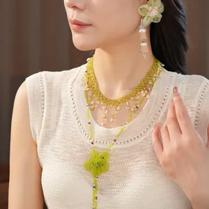 Detail view of Bohemian chiffon flower earrings and green beaded necklace on model.